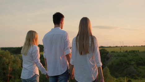 a group of friends enjoy the sunset over a picturesque valley, rear view