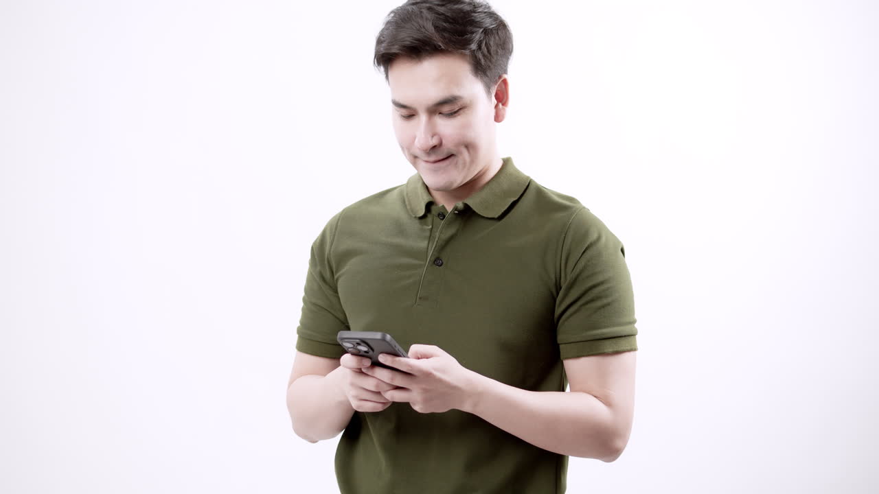 A young man focused his smartphone in a minimalist interior showcasing modern lifestyle and technology use.