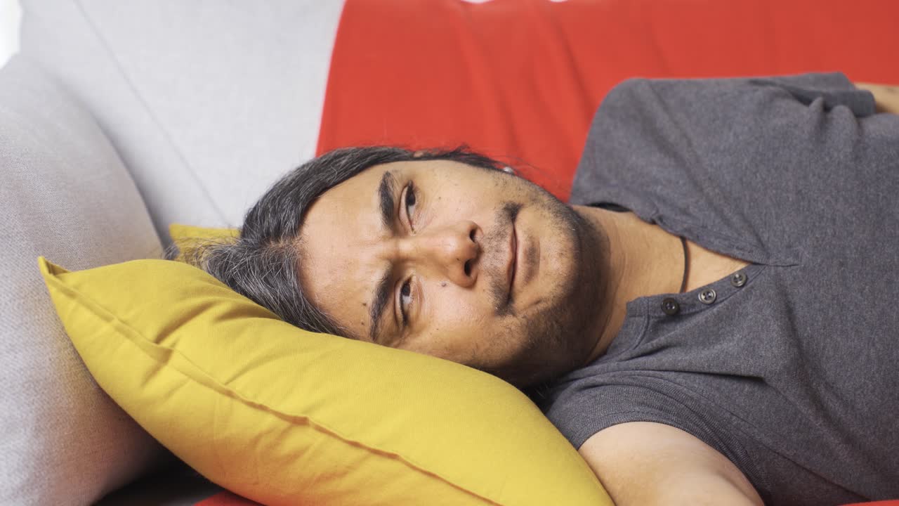 게으른 지루한 남자가 소파에 누워 tv를 보고 있다.