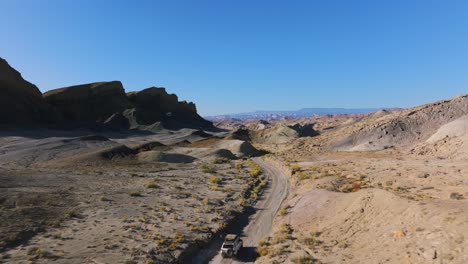 following a white vehicle driving through desert hills, utah, western usa