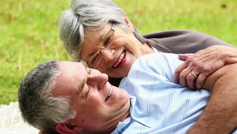 una pareja de ancianos afectuosos relajándose en el parque acostados en una manta