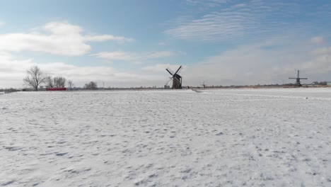 dutch winter windmill snow scene, dolly aerial flight over field