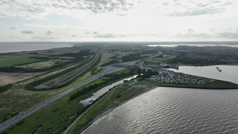 Toll-road-at-entrance-to-Storebelt-bridge-in-Denmark---Aerial-with-backlit-morning-sunrise