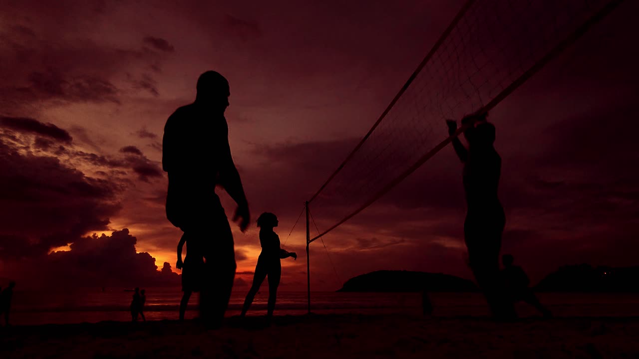 Silhouette di persone che giocano a pallavolo sulla spiaggia al tramonto