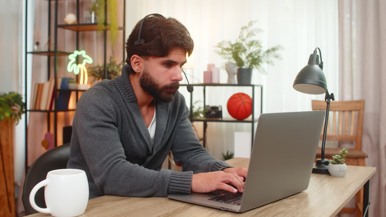 Indian man in headset at laptop friendly support agent listens writes key points customer care calm