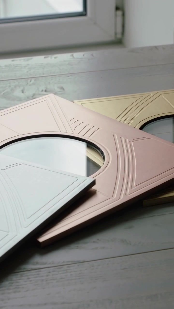 Vertical video: Panning camera showing stacked rose-gold mirrors on sill, revealing embossed detail