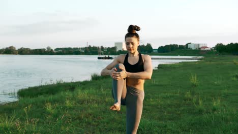 brunette woman practicing yoga in park. girl doing yoga moves on green grass