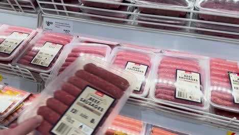 a person chooses packaged sausages from a shelf