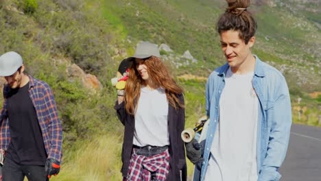 Front-view-of-cool-young-caucasian-skateboarder-walking-with-skateboard-at-countryside-on-road-4k