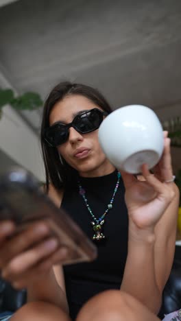 mujer usando el teléfono y sosteniendo una taza