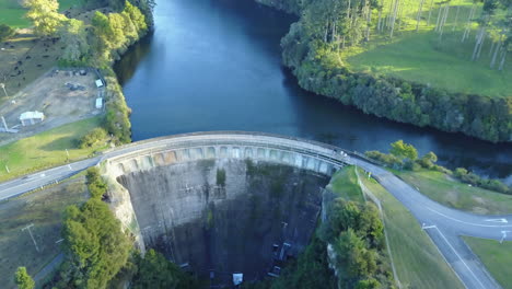 Aerial-drone-shot-of-a-dam-with-blue-water-and-green-trees-with-white-birds