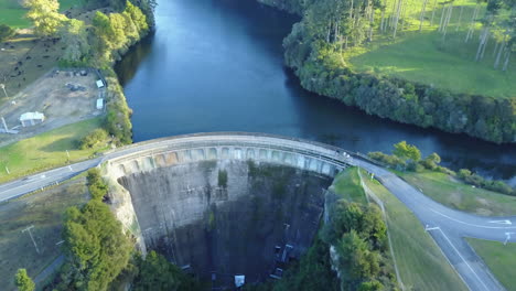 aerial drone shot of a dam with blue water and green trees with white birds