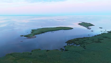 flying above a calm sea and coastline and rotating shot around two small islands in the evening light