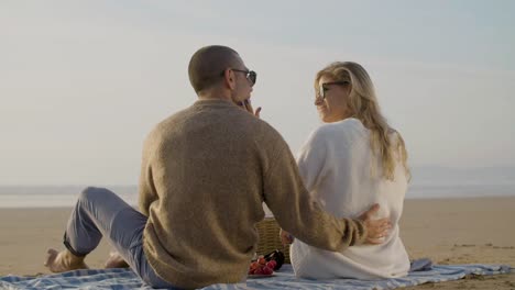 lovely caucasian couple having picnic on seashore at sunset.