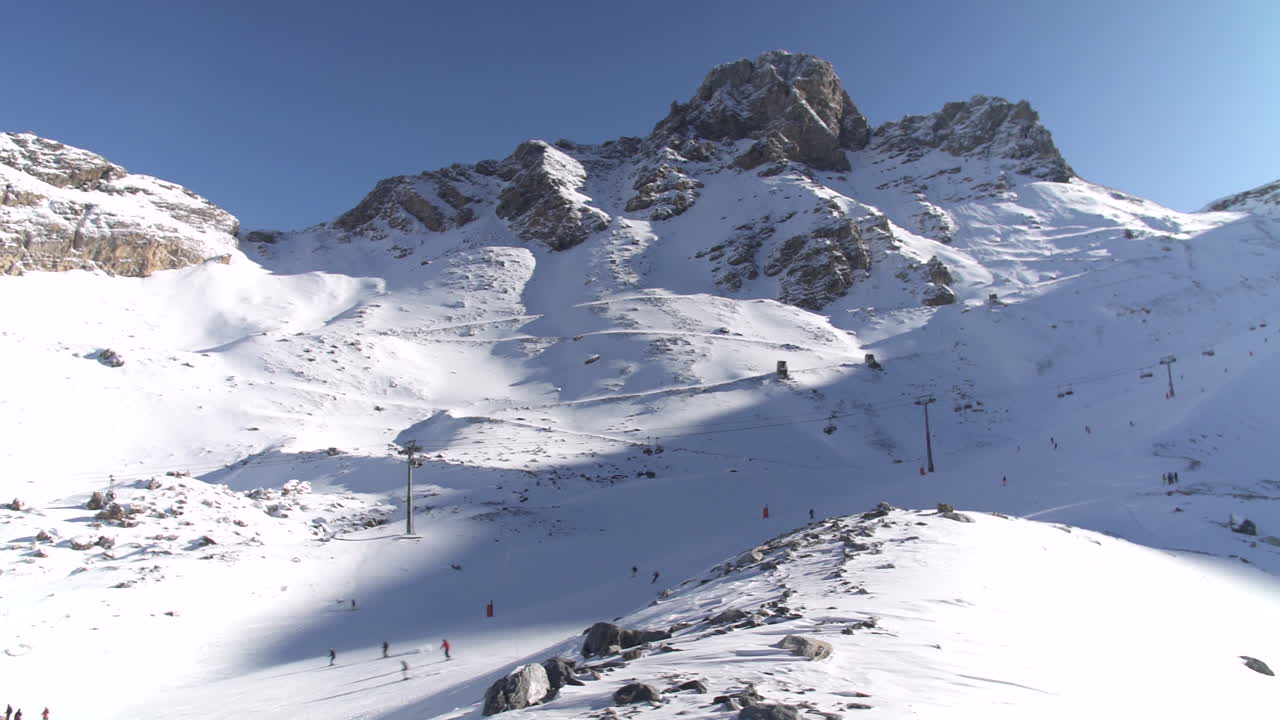 4K Panning shot across a piste on a busy ski day in Tignes, France with people skiing