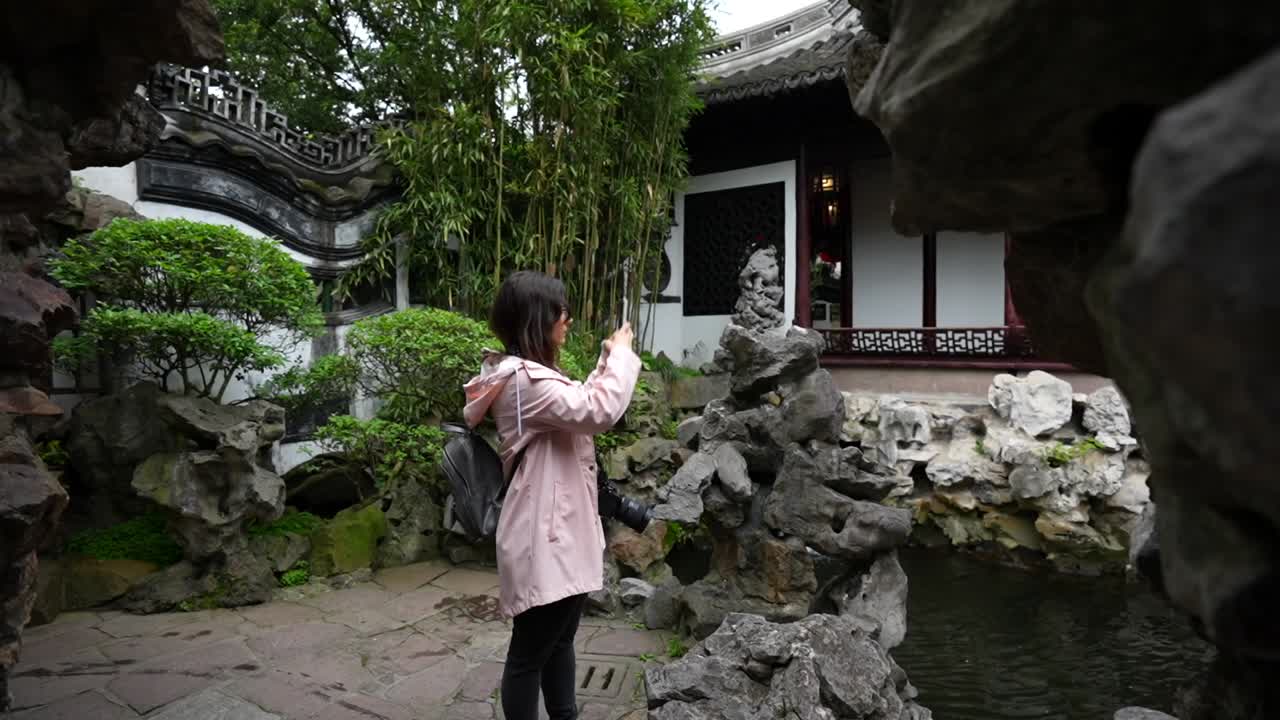 Slow motion of a tourist taking phone photos while holding a professional camera in Yuyuan Garden, Shanghai, China
