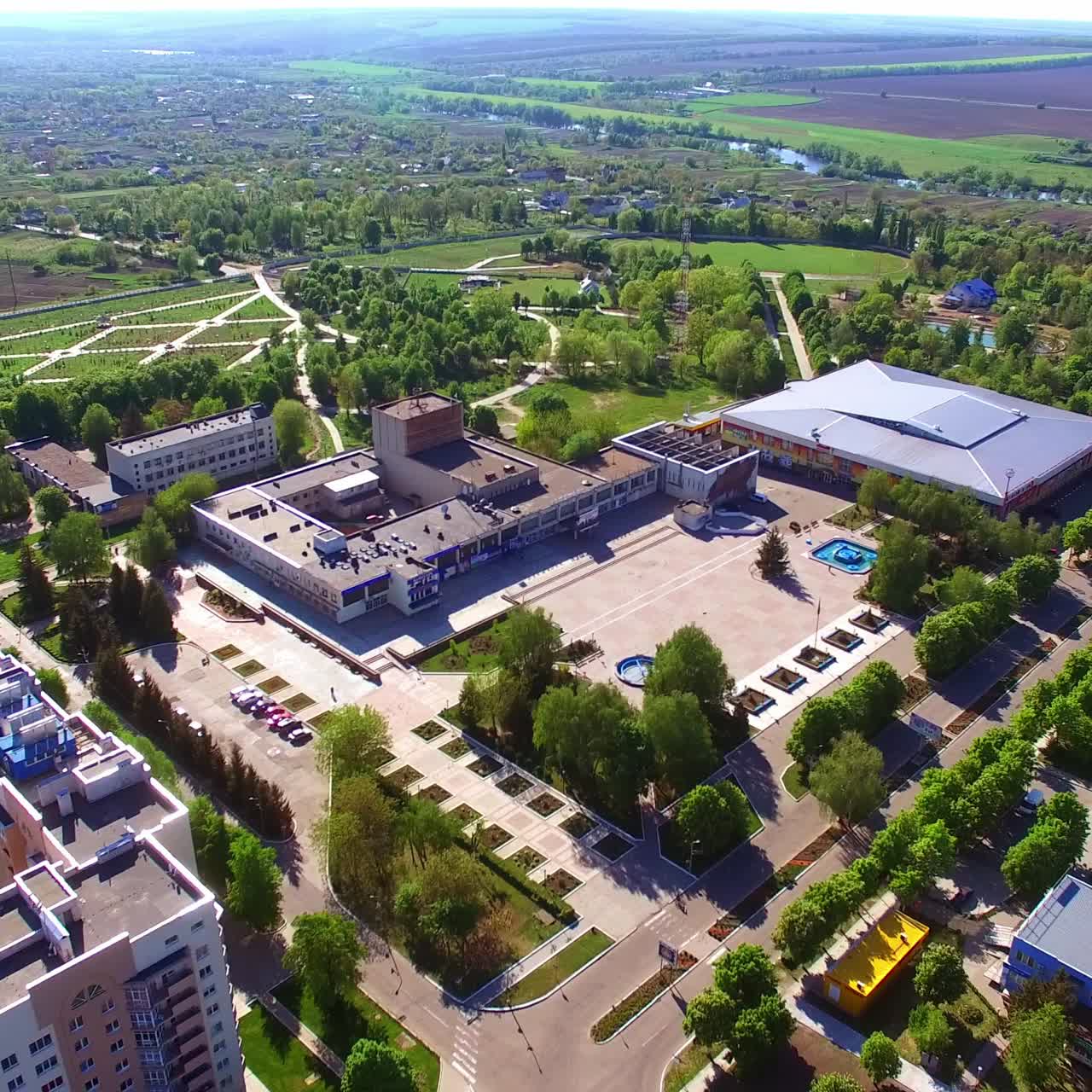 Big green city with residential areas and large shopping malls. Sunny view of the city in summer. Aerial perspective