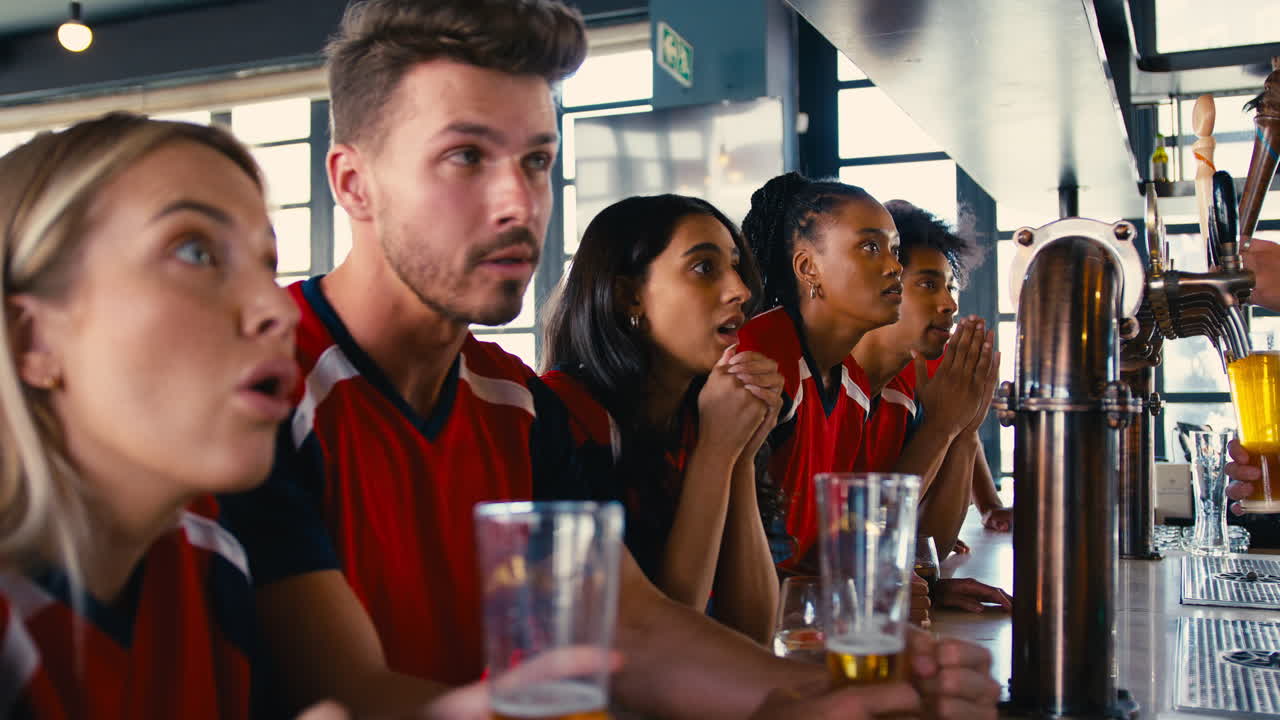 un grupo de amigos decepcionados vistiendo camisetas del equipo en un bar deportivo viendo al equipo perder el juego en la televisión