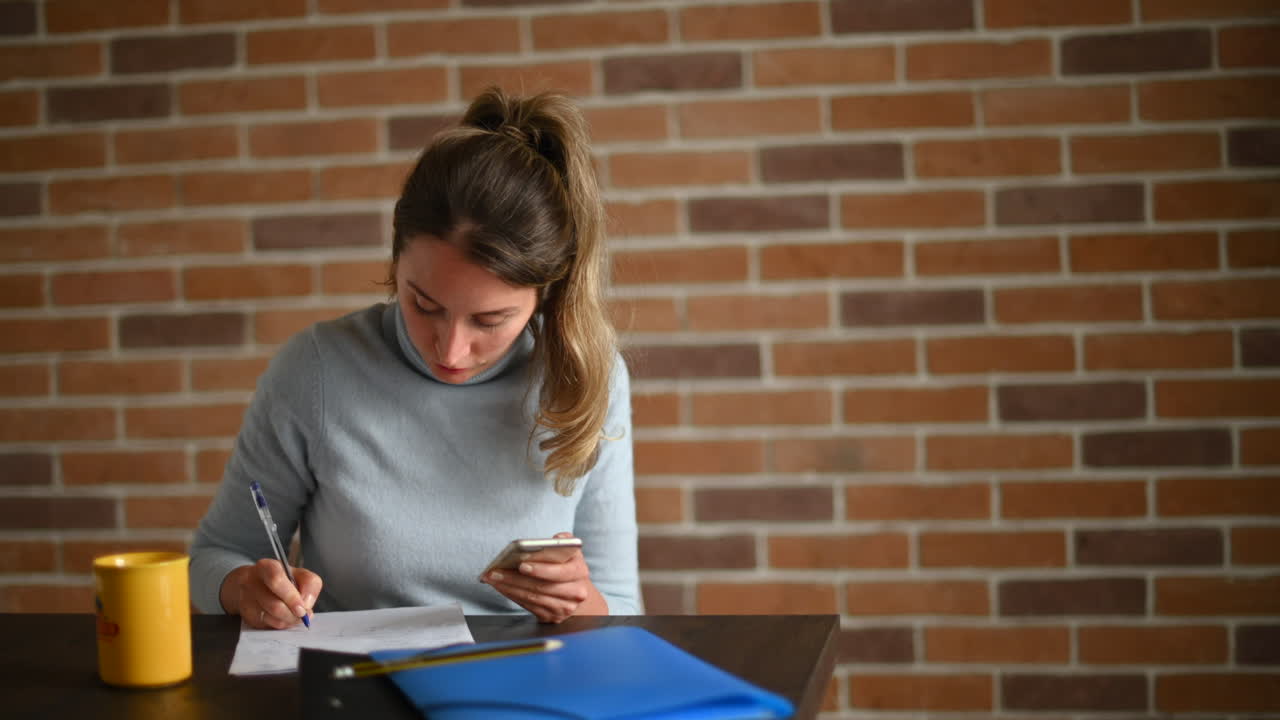 Donna che lavora al cellulare e scrive in ufficio
