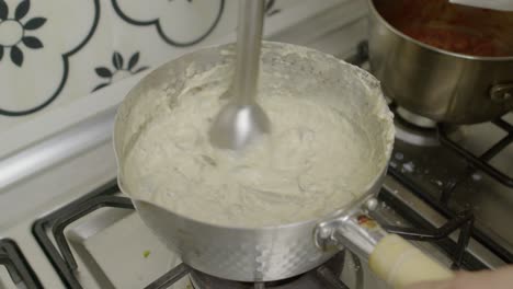 Mashing-mushrooms-with-electric-blender-in-metal-pot