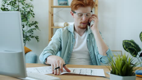 man talking on phone while reviewing house plans