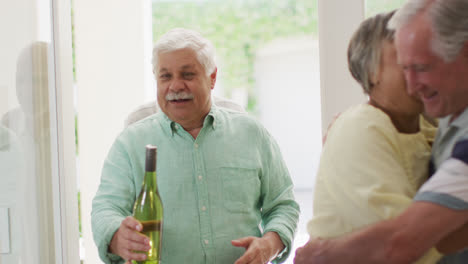 happy couple greeting group of diverse senior male and female friends at front door, slow motion