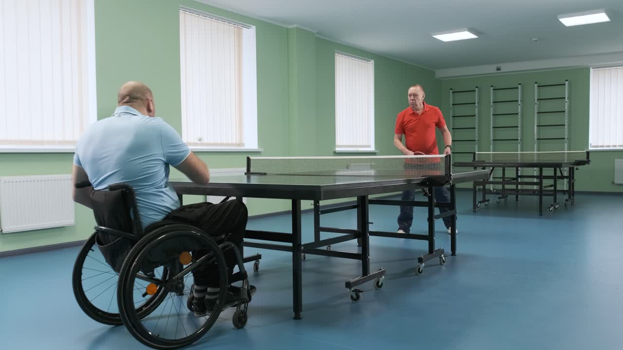 체어에 앉아 있는 남자가 핑핑을 하고, 장애인들이 탁구를 하고, 장애인의 재활, 스포츠.