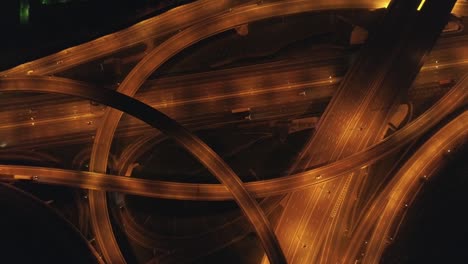 illuminated multi-level road junction and cars traffic at night. drone is spinning around and flying up. aerial vertical shot.