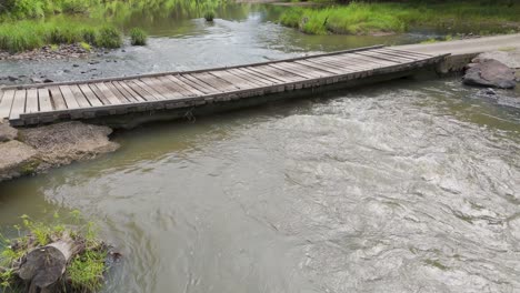 wooden bridge over river rapids in uki, nsw