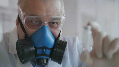 extreme close-up of a scientist in a blue respirator and protective glasses who developed a coronavirus vaccine holding an ampoule of white powder. narcotic substances and painkillers. high quality 4k footage