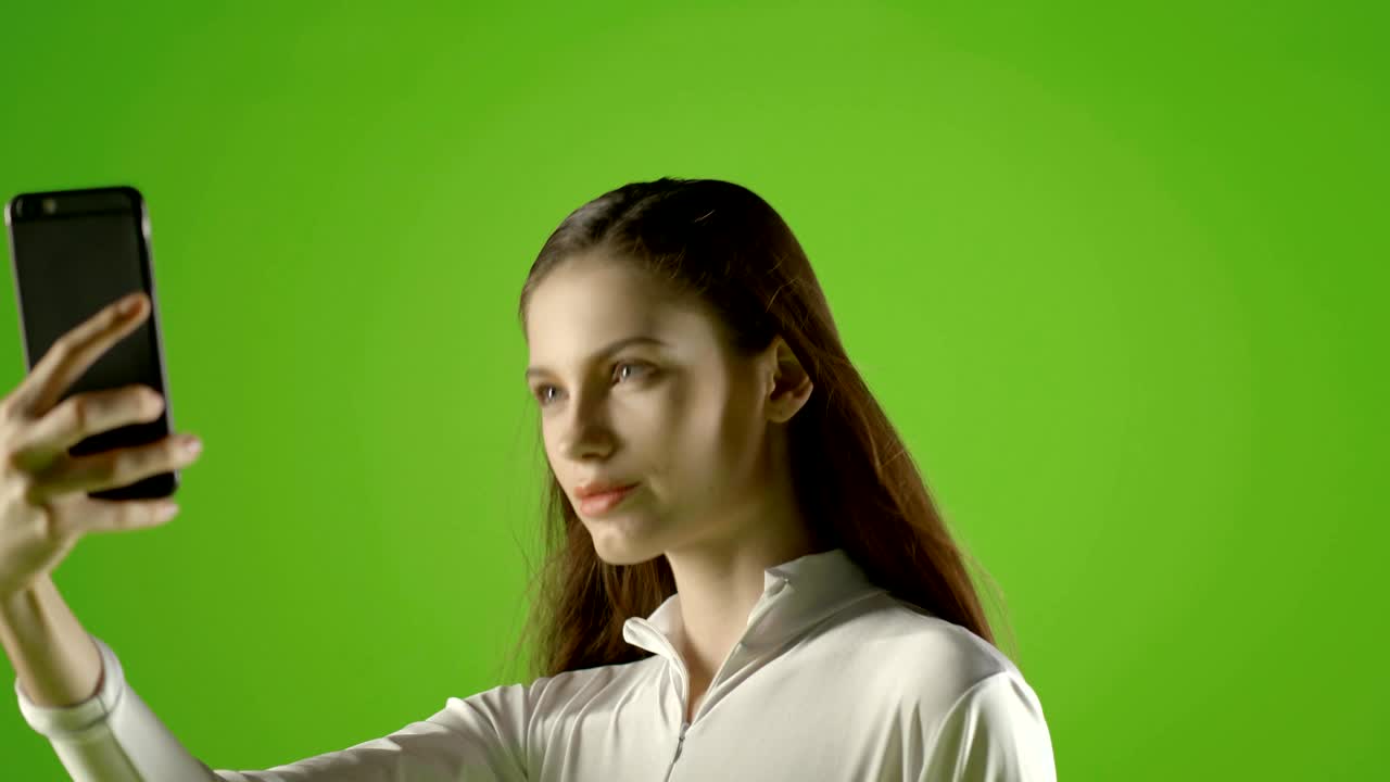 chica atractiva joven modelo de moda interactuar con su teléfono inteligente y tomar selfie pantalla verde prores disparar en ursa mini pro
