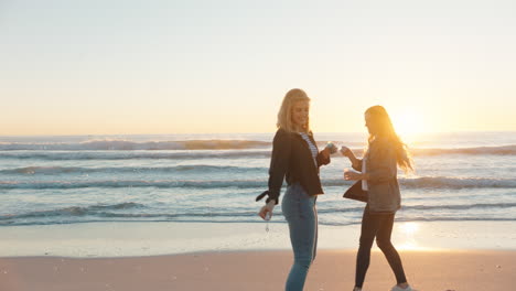 Amigas-Soplando-Burbujas-En-La-Playa-Al-Atardecer-Divirtiéndose-En-Verano-Jugando-Junto-Al-Mar-Disfrutando-De-La-Amistad