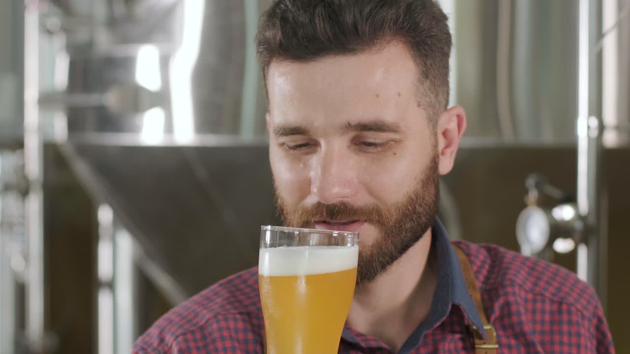 un joven cervecero con un delantal de cuero está probando cerveza en una cervecería moderna