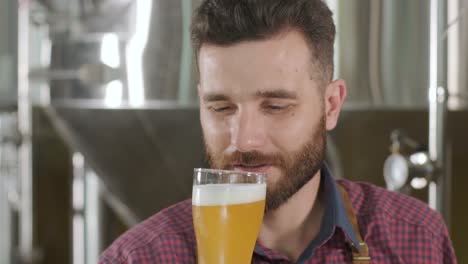 ein junger brauer mit ledervorhang probiert bier in einer modernen brauerei