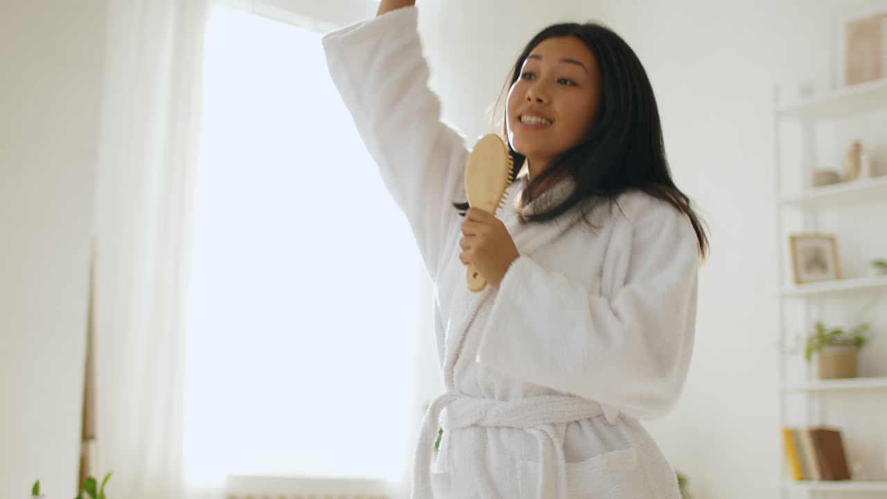 Woman Singing While Combing Her Hair in a Bathrobe