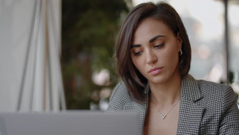 una joven hermosa está sentada en una silla y escribiendo o tomando notas mientras asiste a una clase de video en línea o a una reunión de oficina en una computadora portátil. mujer musulmana moderna que trabaja en línea de forma remota