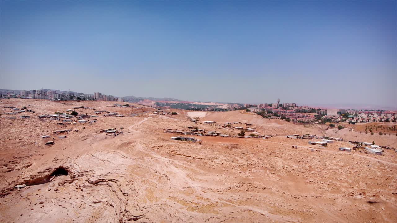 Vista aerea di un campo profughi palestinese in un paesaggio desertico arido con una città in lontananza
