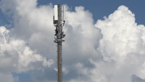 tilt up shot of modern 5g telecommunication tower, cellular network antenna sending signal waves during cloudy day