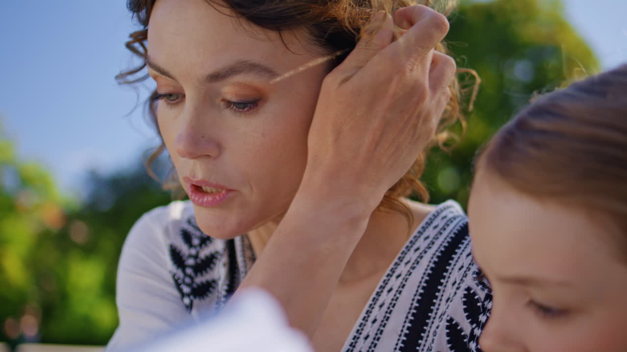 Careful mom reading book with daughter on summer picnic closeup. Happy family