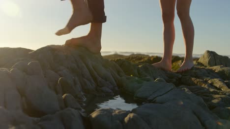 Unterer-Teil-Eines-Paares,-Das-Auf-Einem-Felsen-Am-Strand-Läuft,-4k