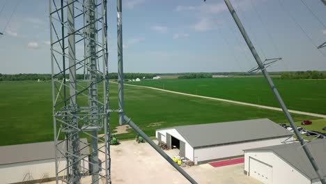 reverse aerial view through industrial steel mast over agricultural silo storage in arcadia farming agribusiness, indiana
