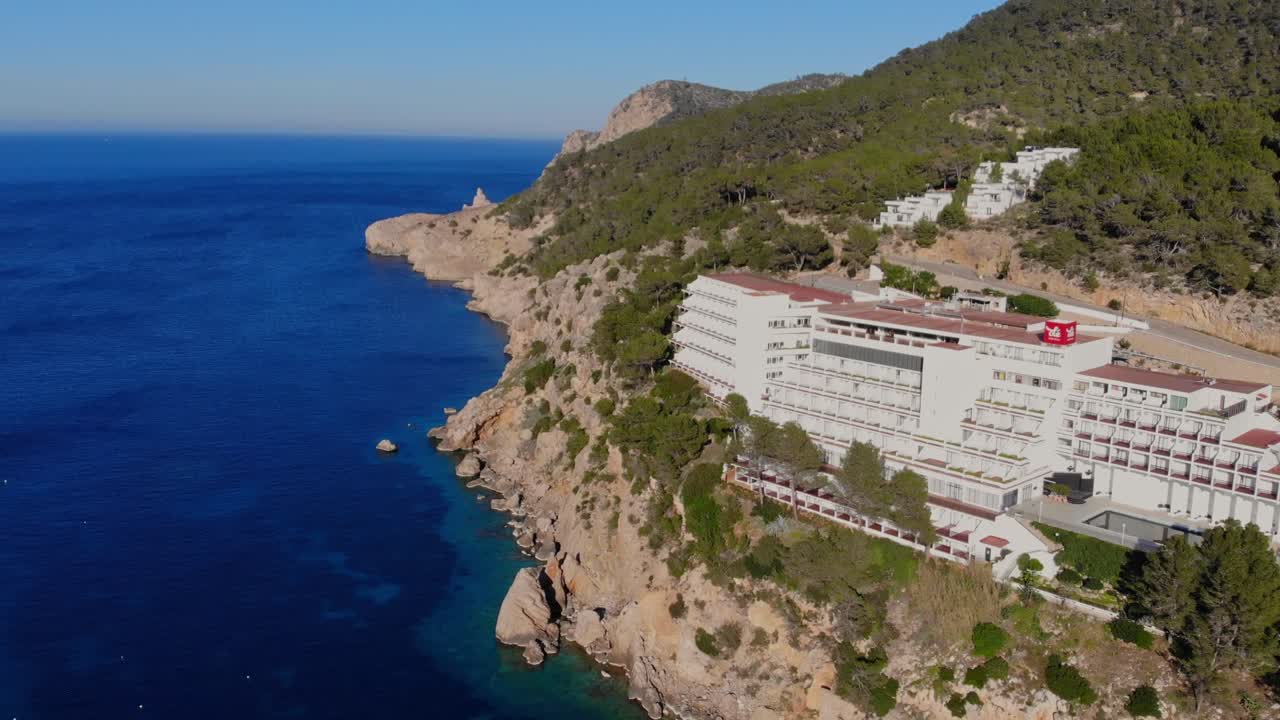 이비자 (ibiza) 의 절벽 해안에 있는 호텔  ⁇ 에서 드론이 상승하고 있습니다.