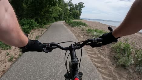 Riding-a-bike-along-a-paved-trail,-that-follows-the-shoreline-beaches-of-Great-Lake-Erie