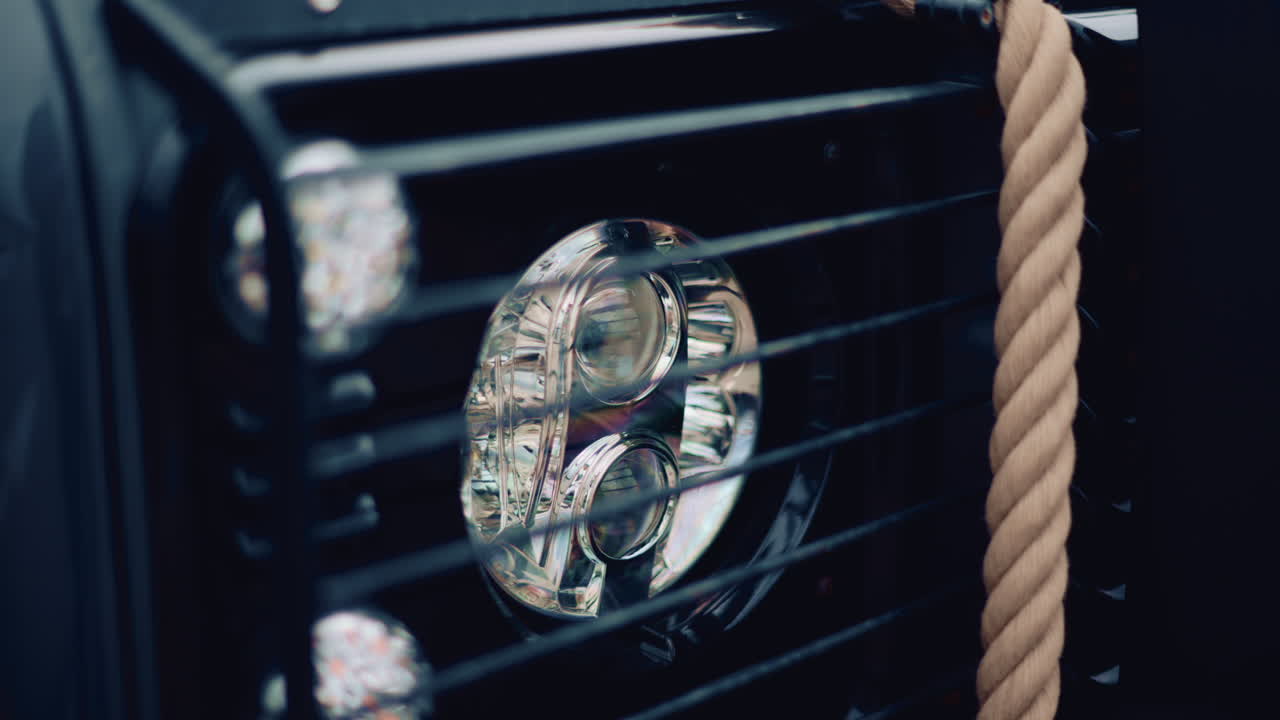 Close up of a luxury car headlight with soft reflections and a rope beside it