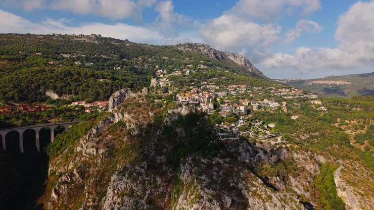 Eze Village, città medievale in cima a una collina, ripresa aerea all'indietro di case sulla scogliera, montagne, foresta e colline costiere, punto di riferimento storico della Costa Azzurra, destinazione di viaggio in Francia