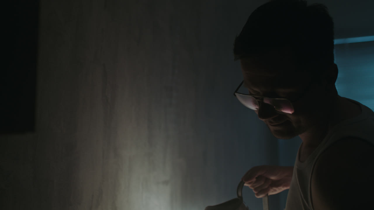 A sad man reads a book at night in his underwear