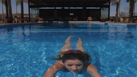 gorgeous woman swimming under water coming out happy slow motion