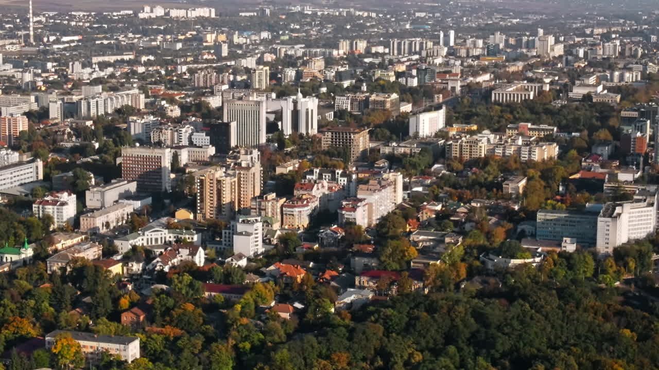 Aerial drone view of Chisinau downtown at sunset. Panorama view of multiple buildings, roads with lush trees. Moldova