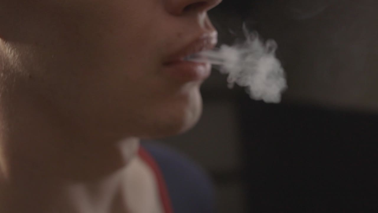 Side View Of A Young Man Vaping With Smoke Coming Out From The Nose And Mouth. - close up