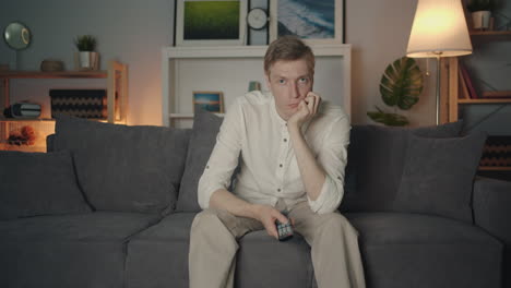 man bored on couch watching tv
